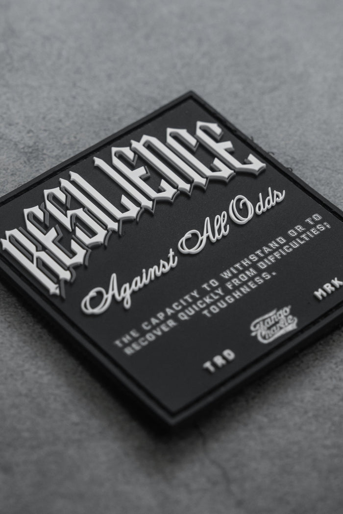 The Resilience - Patch by Tango Charlie Apparel features a black 3D PVC design with “RESILIENCE” in bold white on grey, “Against All Odds” below, plus text defining resilience. Credits note TTD, MRK, and Savage Supply Co. It’s a 3-inch Velcro patch.