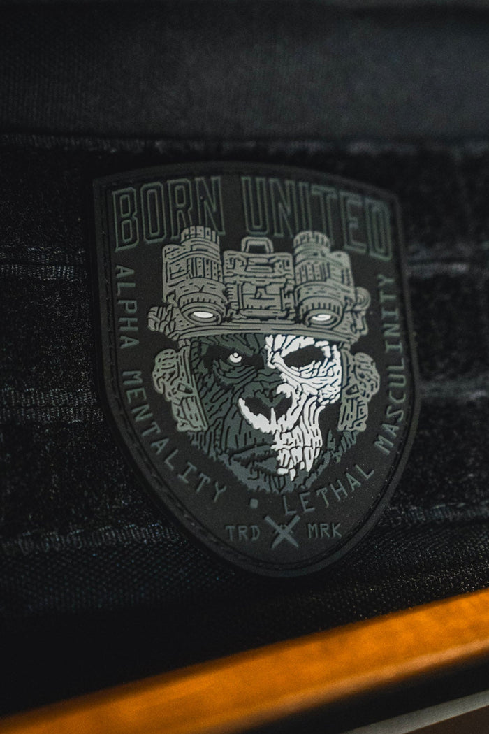 The Alpha Mentality PVC Patch by Born United Private Label showcases a gorilla face in tactical gear on a black background, boldly marked with "Born United" and featuring the emblem "TRD MRK." Embodying alpha mentality and lethal masculinity, this stylish patch is designed for those who lead.