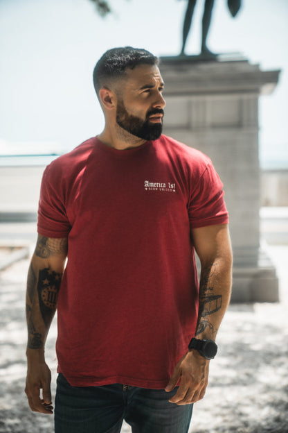 Man wearing a red t-shirt with text, standing outdoors.