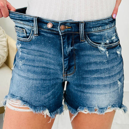 Person wearing blue denim shorts with a white background