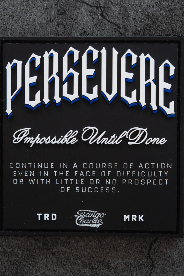 The Persevere - Patch by Tango Charlie Apparel features "PERSEVERE. Impossible Until Done" in white and blue on a textured gray background, resembling a classic 3D PVC or Velcro patch. Perfect for those who keep going against the odds.