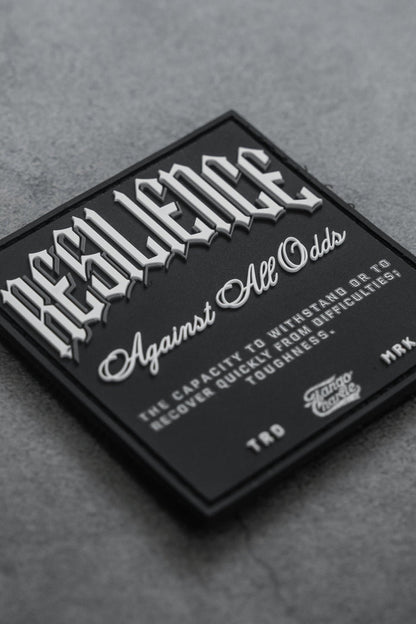 The Resilience - Patch by Tango Charlie Apparel features a black 3D PVC design with “RESILIENCE” in bold white on grey, “Against All Odds” below, plus text defining resilience. Credits note TTD, MRK, and Savage Supply Co. It’s a 3-inch Velcro patch.
