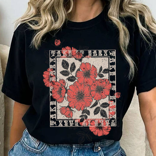 Person wearing a black t-shirt with red floral design and denim shorts.