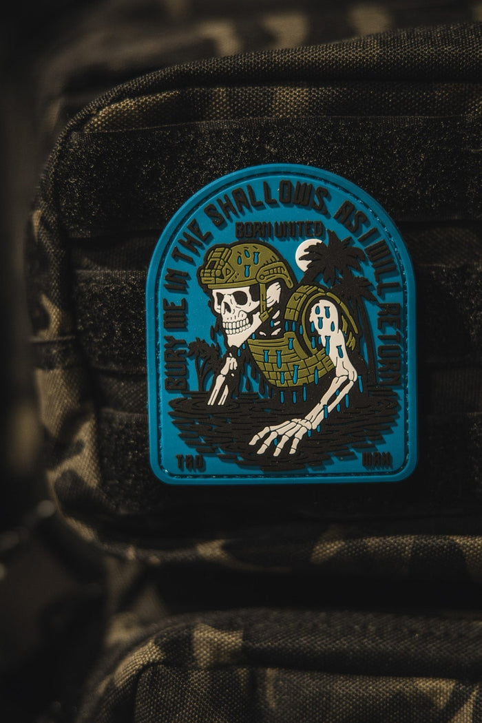 The Born United Private Label The Shallows PVC Patch features a skeleton in military gear rising from water on a camouflage backpack, with the phrase Down in the shallows rise the legends.