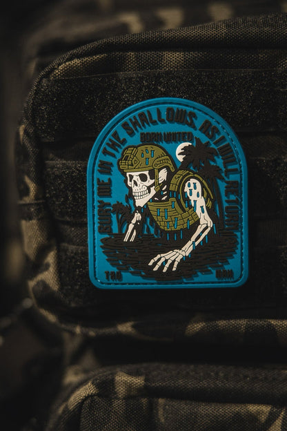 The Born United Private Label The Shallows PVC Patch features a skeleton in military gear rising from water on a camouflage backpack, with the phrase Down in the shallows rise the legends.