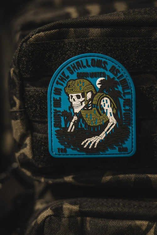 The Born United Private Label The Shallows PVC Patch features a skeleton in military gear rising from water on a camouflage backpack, with the phrase Down in the shallows rise the legends.