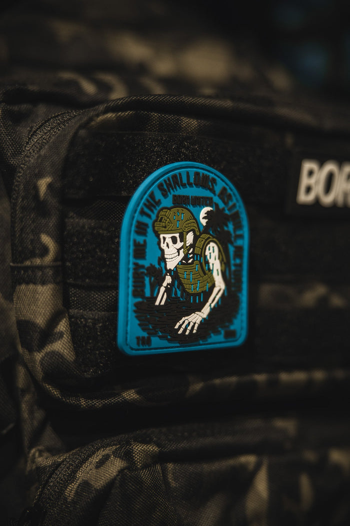 The Shallows PVC Patch by Born United Private Label features a skeleton in military gear rising from water on a blue and black camo background, with DOWN IN THE SHALLOWS REAP THE DEEP around the edge.
